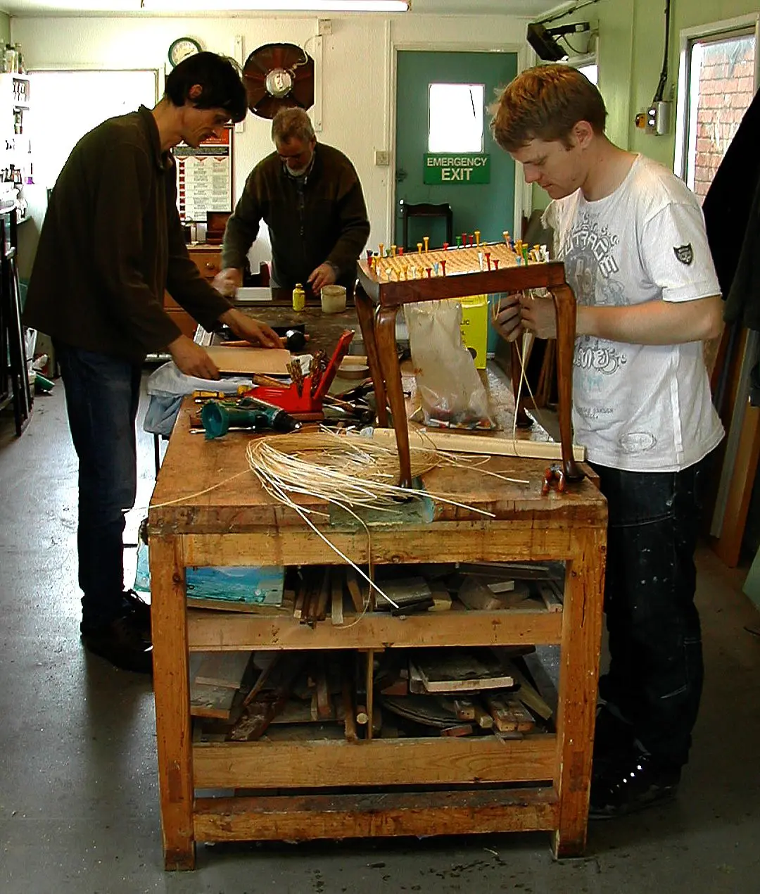 Beneficiaries working on chair caning and restoration